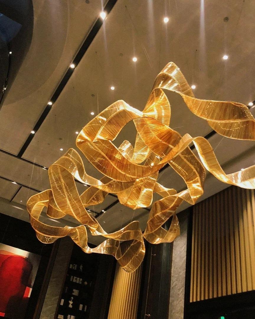 Radiant flow chandelier modern LED chandelier India luxury ribbon chandelier with ambient lighting designer flowing chandelier for modern interiors contemporary LED chandelier for living room India illuminated gold chandelier for luxury spaces modern suspension chandelier for dining area premium LED chandelier for hotel lounge lighting sculptural ribbon chandelier for high ceiling interiors elegant modern chandelier for entrance hall luxury ambient chandelier for interior designers India